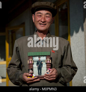 North Korean man showing his son picture serving in the army in a Mickey mouse frame, North Hamgyong Province, Jung Pyong Ri, North Korea Stock Photo