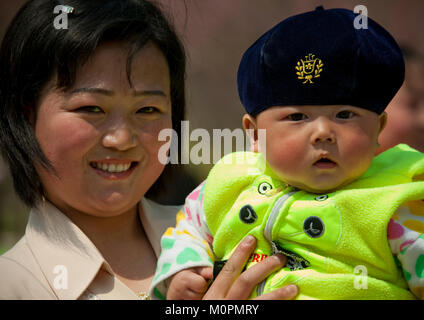 North Korean mother holding her baby who wears a beret in her arms, Pyongan Province, Pyongyang, North Korea Stock Photo
