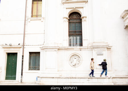 Two boys playing near St. Marks Square in Venice, Italy climbing on a building Stock Photo