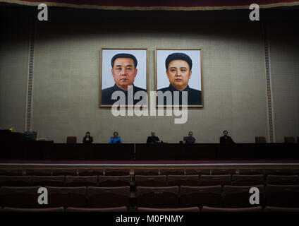 Tourists posing below the portraits of the Leaders in a conference room of the Grand people's study house, Pyongan Province, Pyongyang, North Korea Stock Photo
