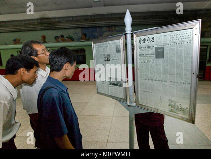 North Korean people reading the offical state newspaper in a subway station, Pyongan Province, Pyongyang, North Korea Stock Photo