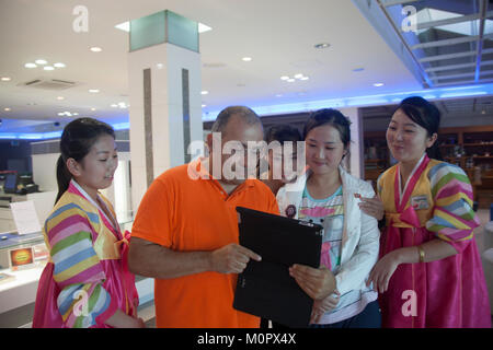 French tourist showing his ipad to saleswomen in the former meeting point between families from North and south, Kangwon-do, Kumgang, North Korea Stock Photo