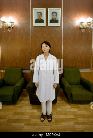 North Korean doctor at the maternity posing below the official portraits of the Dear Leaders, Pyongan Province, Pyongyang, North Korea Stock Photo