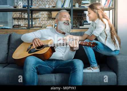 Cheerful grandfather singing for his adorable granddaughter Stock Photo
