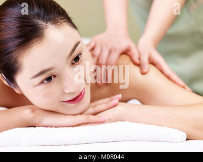 close-up of face of a beautiful young asian woman lying on front on bed receiving massage in spa salon. Stock Photo