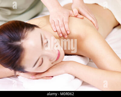 young asian woman lying on front on bed receiving massage in spa salon. Stock Photo