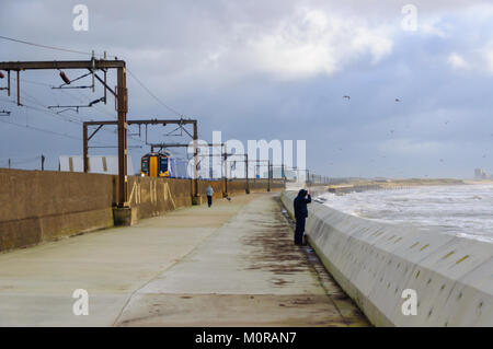 Saltcoats, Scotland, UK. 24th January  2018. UK Weather: A train passing through Saltcoats travels next to the coastline as high winds cause waves to crash against the sea wall. Storm Georgina is the seventh named storm of the season and is forecast to bring high wind and rain sweeping easterly across Britain. Credit: Skully/Alamy Live News Stock Photo