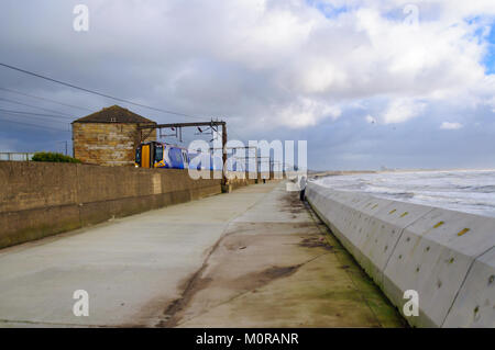 Saltcoats, Scotland, UK. 24th January  2018. UK Weather: A train passing through Saltcoats travels next to the coastline as high winds cause waves to crash against the sea wall. Storm Georgina is the seventh named storm of the season and is forecast to bring high wind and rain sweeping easterly across Britain. Credit: Skully/Alamy Live News Stock Photo