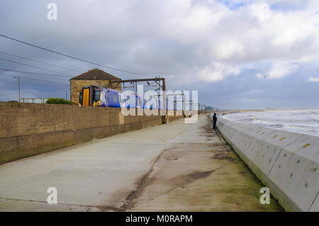 Saltcoats, Scotland, UK. 24th January  2018. UK Weather: A train passing through Saltcoats travels next to the coastline as high winds cause waves to crash against the sea wall. Storm Georgina is the seventh named storm of the season and is forecast to bring high wind and rain sweeping easterly across Britain. Credit: Skully/Alamy Live News Stock Photo