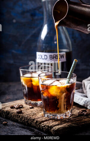 Pouring homemade vanilla flavoured coffee creamer into a glas with iced coffee Stock Photo