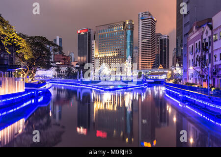 Office buildings reflect in the water of the Klang river in front of the Jamek mosque (masjid) in the heart of Kuala Lumpur in Malaysia at night. The  Stock Photo
