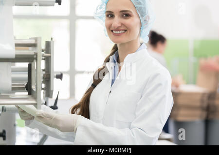 Happy employee wearing lab coat while handling sterile wipes in  Stock Photo