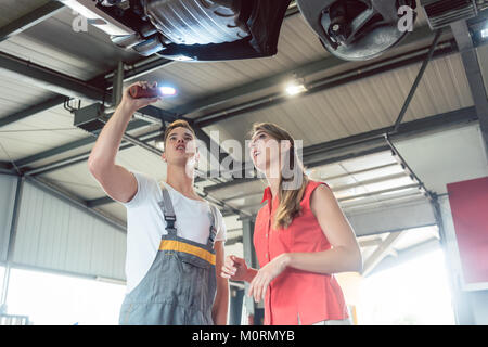 Reliable auto mechanic checking the car of a woman in a modern a Stock Photo