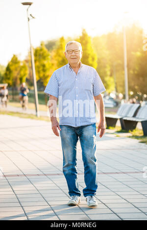 Happy senior man is walking on sunny day. Stock Photo