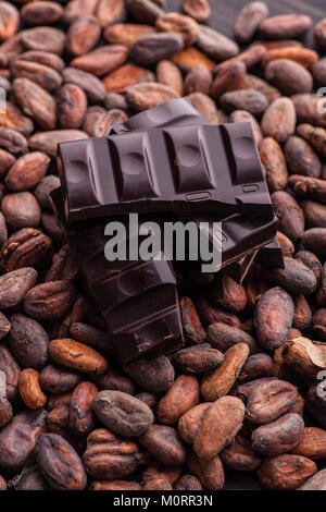 Piece of dark chocolate on a pile of raw cocoa beans Stock Photo