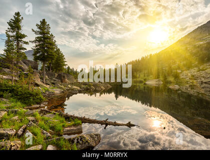 Summer morning over little lake. Sun rays shine between clouds. Ergaki Nature Park. Krasnoyarsk region Russia Stock Photo