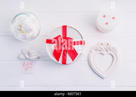 White round box with red ribbon, sweets, candle and photo frame in shape of heart. Gifts for Valentine's Day for a loved one. Celebrating love. Festive gift. Lovers of the heart. Stock Photo