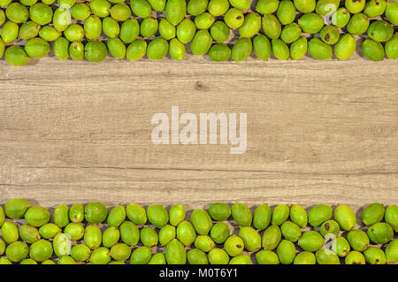Green young walnuts in husks on the side two rows on wooden table Stock Photo
