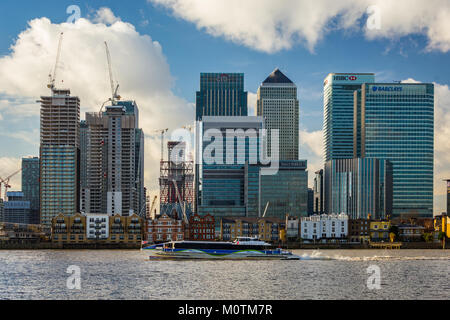 MBNA high speed catamaran on Thames heading past modern skyscrapers of Canary Wharf, January 2018, Greenwich London Stock Photo
