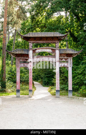 The old wooden chinese gate in the garden of tropical agronomy in Paris has lost its original red color because of the action of sunlight and rain. Stock Photo