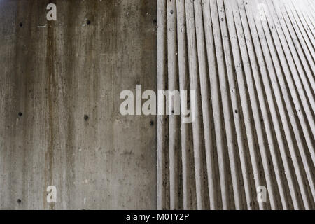 Abstract view of the surface of a concrete structure, half smooth, half grooved, under a raking light. Stock Photo