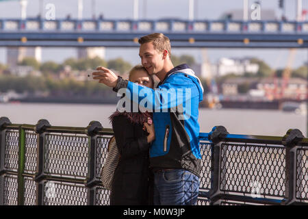 A young couple taking a selfie photograph in front of Tower Bridge, London, England Stock Photo
