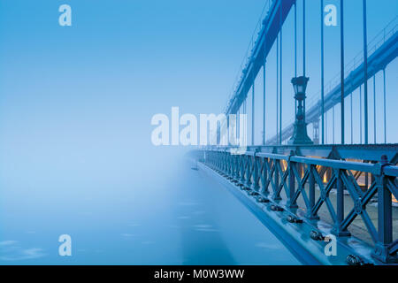 Szechenyi chain bridge in heavy blue fog with no visible coast. Budapest Stock Photo