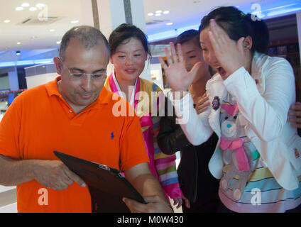 French tourist showing his ipad to North Korean saleswomen, Kangwon-do, Kumgang, North Korea Stock Photo