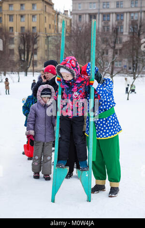 ST. PETERSBURG, RUSSIA-FEB 22, 2017: Young girl tries to walk on stilts during the Carnival celebration. Maslenitsa is an Eastern Slavic religious and Stock Photo