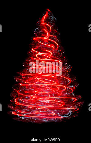 A small spinning artifical Christmas tree producing a cone-shaped corkscrew of blurred red light. Stock Photo