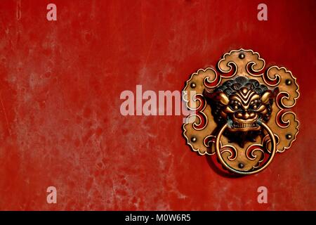Traditional brass lion door knocker on red lacquer Chinese temple door Stock Photo