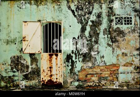 Weathered back of a shop house with rusty iron bi fold door and traditional ventilation duct. Stock Photo
