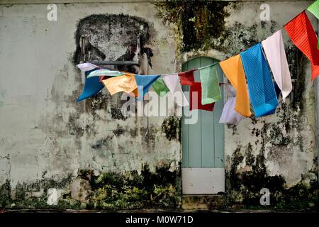 Traditional Buddhist prayer flags hanging on a clothes line on the weathered of a shop house in Geylang Singapore Stock Photo