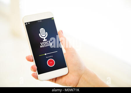 Woman holding a pink gold generic smartphone showing voice message recording Stock Photo