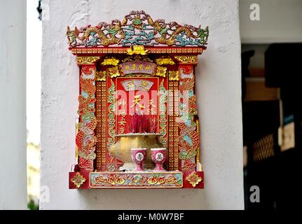 Traditional Chinese Buddhist street shrine hanging outside a shop house in Geylang, Singapore Stock Photo