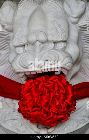 Traditional stone Chinese lion statue decorated with red silk to celebrate Chinese Lunar New Year. Stock Photo