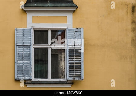 Close up view of old window with open shutters on yellow wall Stock Photo