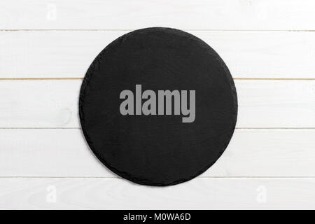 Black slate round stone on wooden background, top view, copy space. Stock Photo