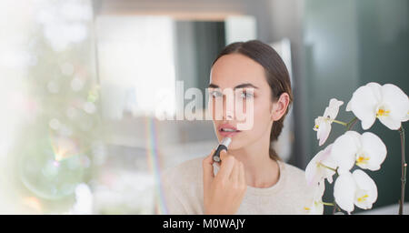 Portrait brunette woman applying lipstick Stock Photo