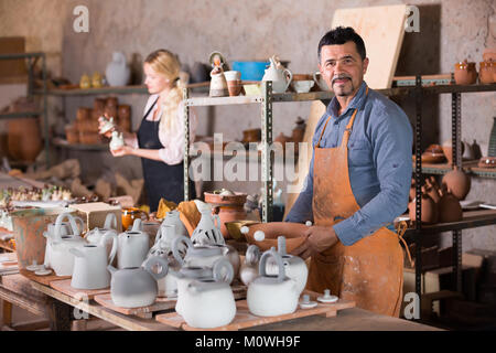 portrait of two joyful smiling potters working with pottery wheel in ...
