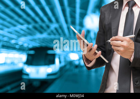 Businessman using the tablet on Abstract blurred photo of sky train station with people background, blue color tone Stock Photo