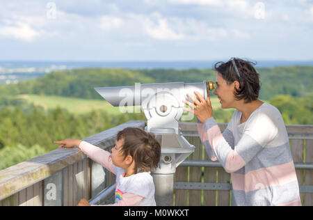 Mother and her daughter looking through a viewing binocular Stock Photo