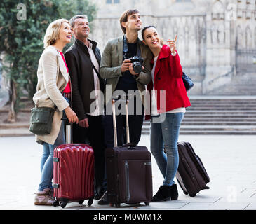 Two couples of tourists in casual with baggage stroll along the streets outdoors Stock Photo