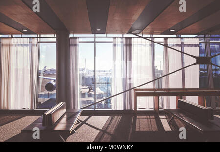 Retro stylized picture of empty seats in an airport departure hall, travel and transportation concept. Stock Photo