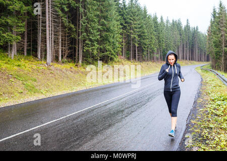Young sporty woman jogging on mountain road. Running fitness girl in sportswear outdoor image with copy space Stock Photo