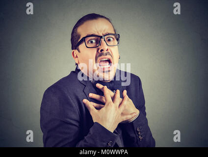 Young man in formal clothing having panic attack while posing on gray. Stock Photo