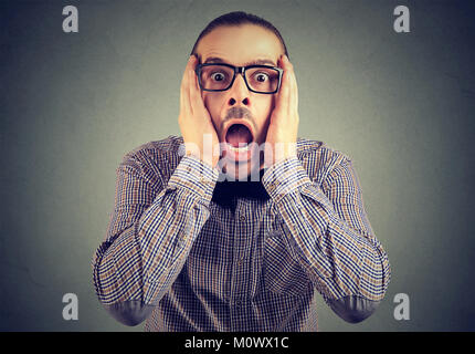 Young formal man in eyeglasses touching head and looking at camera in great astonishment. Stock Photo