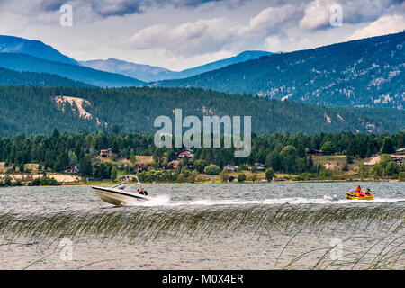 Speedboat pulling woman and young girl in rubber boat, Lake Windermere, Columbia Valley, Purcell Mountains, near Invermere, British Columbia, Canada Stock Photo
