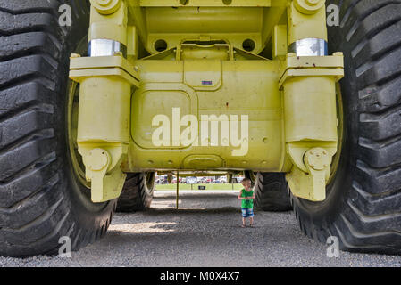 Small child exploring Terex Titan, haul truck for open pit mines, once the largest truck in the world, on display in Sparwood, British Columbia Stock Photo