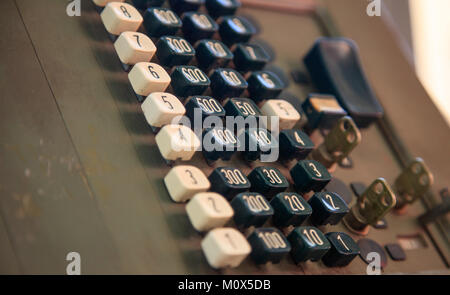 Old-fashioned cashier had been used for retail trade. Close up view with details, brown background. Stock Photo